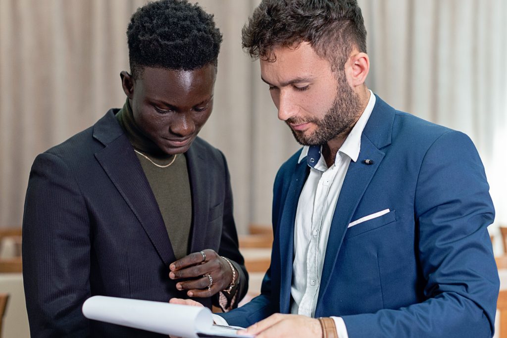 pexels-photo-8729933-8729933 Two businessmen in suits review a contract indoors, focusing on the document.